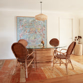 Leila rattan dining chairs styled around the Laguna Dining Table, showing woven backrests and curved arms.